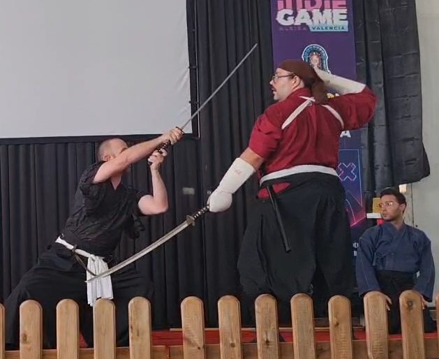 Dos practicantes cruzan sus espadas durante una exhibición en un escenario